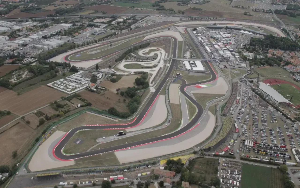 Vista aerea del circuito di San Marino, con tribune piene di spettatori e un vasto parcheggio.