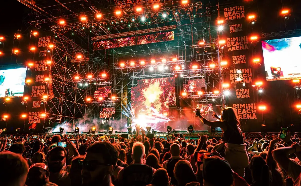 Folla in delirio al concerto al Rimini Beach Arena, luci e musica per un'indimenticabile serata.