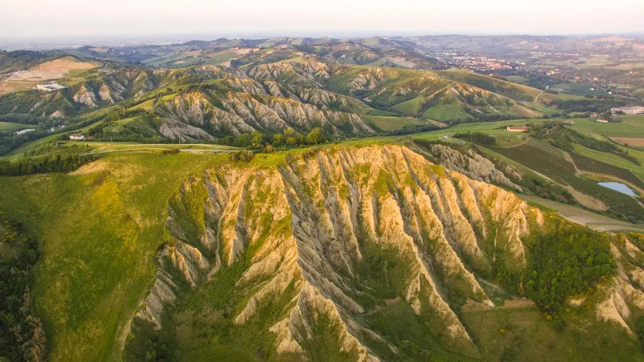 Paesaggio collinare dell'Emilia Romagna, con calanchi argillosi e verdi prati, ideale per il trekking.