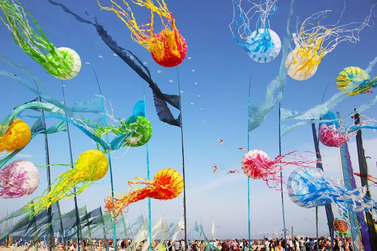 Coloratissime meduse volanti animano il cielo azzurro, un'allegra Pasquetta in Romagna con la spiaggia gremita di gente.