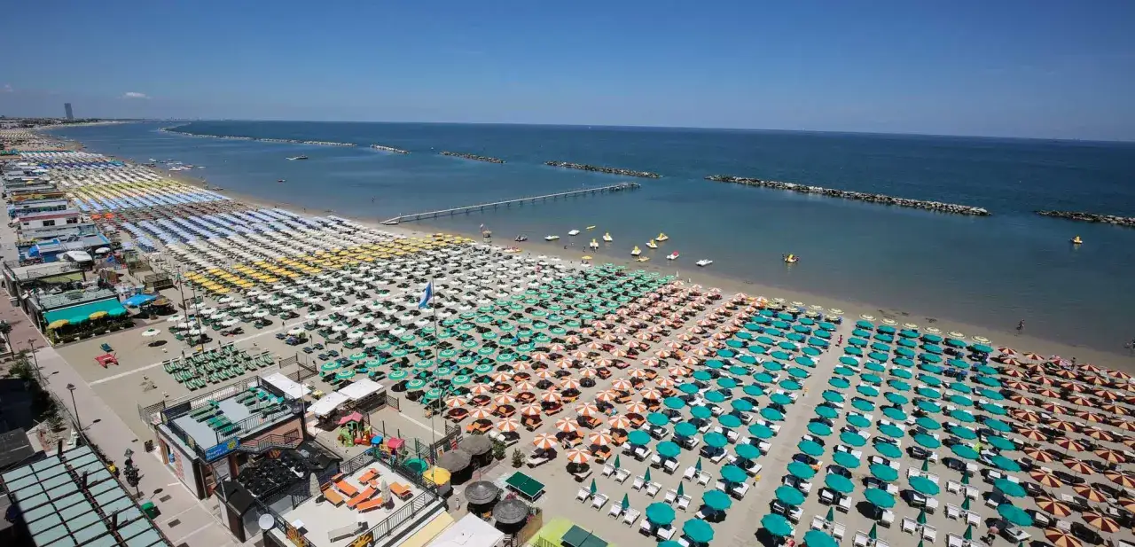 Spiaggia affollata con file ordinate di ombrelloni colorati e lettini, ideale per chi cerca dove andare al mare in Emilia Romagna.
