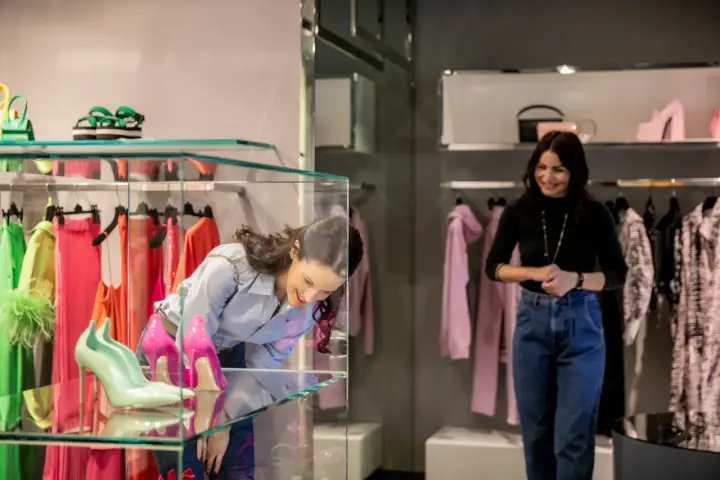 Ragazza ammira scarpe in vetrina, tra i colorati negozi di Milano Marittima.