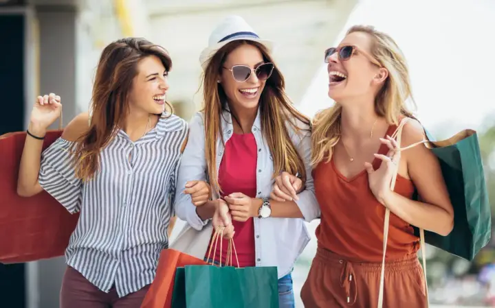 Tre amiche ridono felici con borse della spesa, dopo un pomeriggio di shopping nel cesenatico centro negozi.