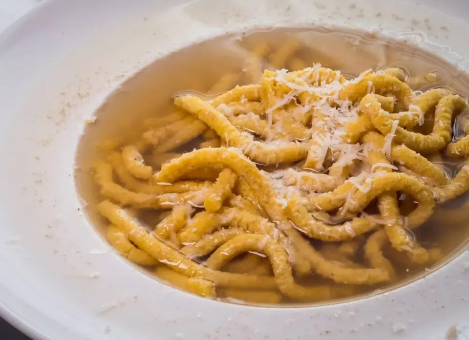Passatelli in brodo, un classico dei piatti tipici romagnoli, con abbondante parmigiano grattugiato.